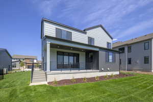 Rear view of house with a lawn and covered porch