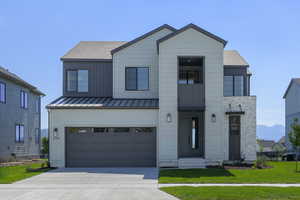View of front of property featuring an attached garage, driveway, a shingled roof, and a standing seam roof