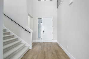 Entryway with stairs, luxury vinyl finished floors, and a high ceiling