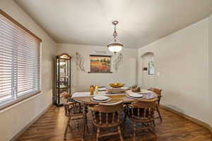 Dining room with dark wood-style flooring and arched walkways