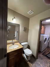 Bathroom featuring vanity, separate washer and dryer, and dark tile patterned floors