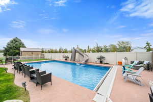View of pool with a water slide, a patio, and a fenced backyard