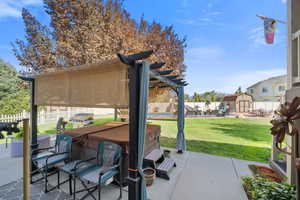 Fenced backyard with a patio area, a storage unit, and a hot tub