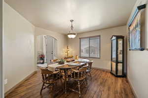 Dining room with arched walkways and dark wood-style flooring