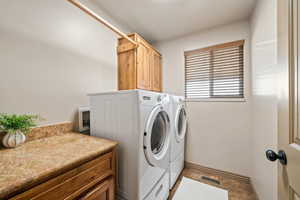 Laundry room with cabinet space, washing machine and dryer, and stone finish floors