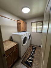 Laundry area with cabinet space, washing machine and clothes dryer, and dark tile patterned floors