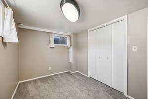 Unfurnished bedroom featuring light colored carpet, a textured ceiling, and a closet