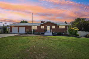 Ranch-style home featuring an attached garage, concrete driveway, brick siding, and a chimney