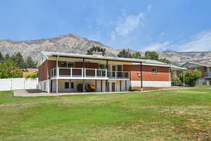 Rear view of property featuring a mountain view, a yard, brick siding, and a chimney