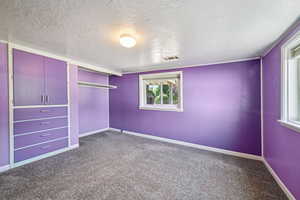 Unfurnished bedroom featuring dark colored carpet, a closet, and a textured ceiling