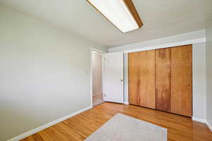 Unfurnished bedroom with a textured ceiling, a closet, and light wood-style floors