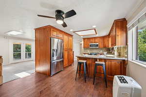 Kitchen with plenty of natural light, a peninsula, stainless steel appliances, light stone counters, and a textured ceiling