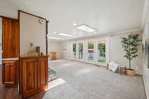 Living room with a skylight, carpet, crown molding, recessed lighting, and french doors