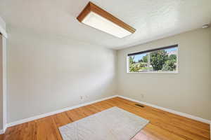 Unfurnished Bedroom with light wood-type flooring and a textured ceiling