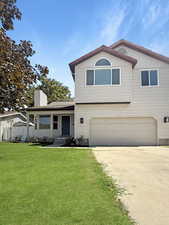 View of front of home with covered porch, driveway, an attached garage, and a chimney