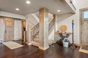 Entryway with dark wood finished floors, stairs, a textured ceiling, and recessed lighting