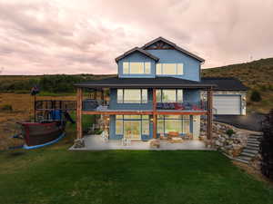 Back of property featuring a patio, a lawn, a balcony, and a garage