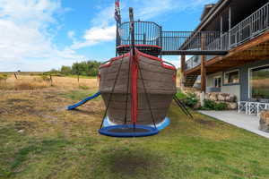 View of jungle gym with a patio area, a trampoline, and a lawn