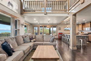 Living area featuring dark wood-type flooring, a textured ceiling, recessed lighting, a chandelier, and beamed ceiling