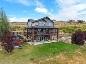 Rear view of house featuring a patio, a lawn, and a balcony