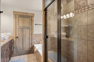 Full bathroom featuring a shower stall, a bath, vanity, and light tile patterned floors