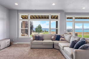 Carpeted living room with a water view, a textured ceiling, and recessed lighting