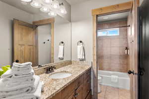 Bathroom with vanity, bathing tub / shower combination, and light tile patterned flooring