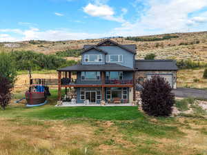 Back of property with a patio, a garage, a lawn, driveway, and a balcony