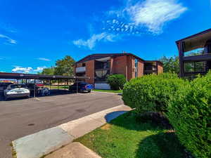 View of building exterior with covered and uncovered parking