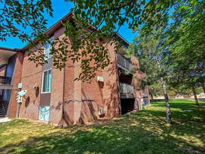 Charming brick exterior surrounded by mature trees with private balconies and grassy common areas.