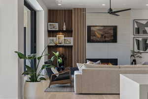 Living area with a large fireplace, a ceiling fan, recessed lighting, and wood finished floors