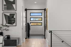 Corridor featuring a barn door, light wood-style floors, and washer / clothes dryer