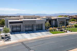 Contemporary house featuring stone siding, an attached garage, a mountain view, and stucco siding
