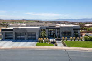 Modern home featuring stone siding, a garage, a front lawn, and a mountain view