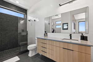 Full bathroom featuring vanity, healthy amount of natural light, a walk in shower, dark tile patterned flooring, and recessed lighting