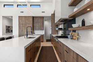 Kitchen featuring open shelves, backsplash, light stone counters, modern cabinets, and light wood-type flooring