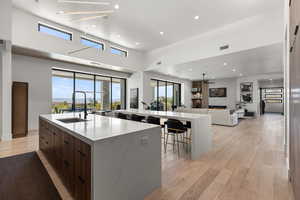 Kitchen featuring modern cabinets, a fireplace, light stone counters, recessed lighting, and open floor plan