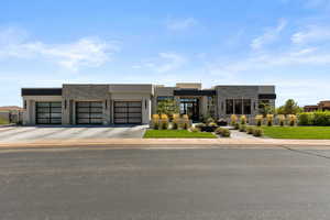 Contemporary house with stone siding, concrete driveway, an attached garage, stucco siding, and a front lawn