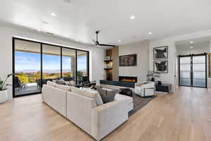Living room with a barn door, a mountain view, recessed lighting, light wood-style flooring, and a tiled fireplace