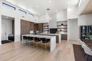 Kitchen with modern cabinets, open shelves, a high ceiling, light stone counters, and light wood-style flooring