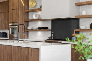 Kitchen featuring open shelves, modern cabinets, brown cabinetry, and backsplash