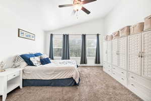 Bedroom featuring light carpet, vaulted ceiling, and a ceiling fan
