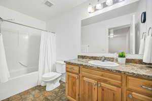 Full bath featuring shower / bath combo, vanity, and stone finish flooring