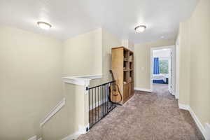 Hall featuring an upstairs landing and carpet flooring