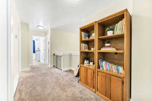 Corridor with an upstairs landing and light carpet