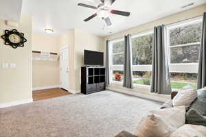 Living room with light colored carpet and a ceiling fan