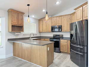 Kitchen with stainless steel appliances, a peninsula, hanging light fixtures, light wood-type flooring, and recessed lighting