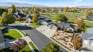 Aerial view of residential area featuring a mountainous background and a golf club