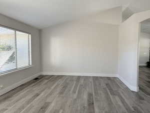 Spare room with light wood-type flooring and vaulted ceiling