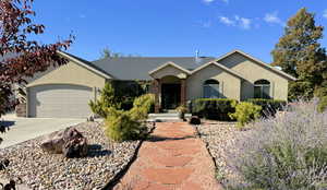 Single story home with stucco siding, a garage, driveway, and roof with shingles